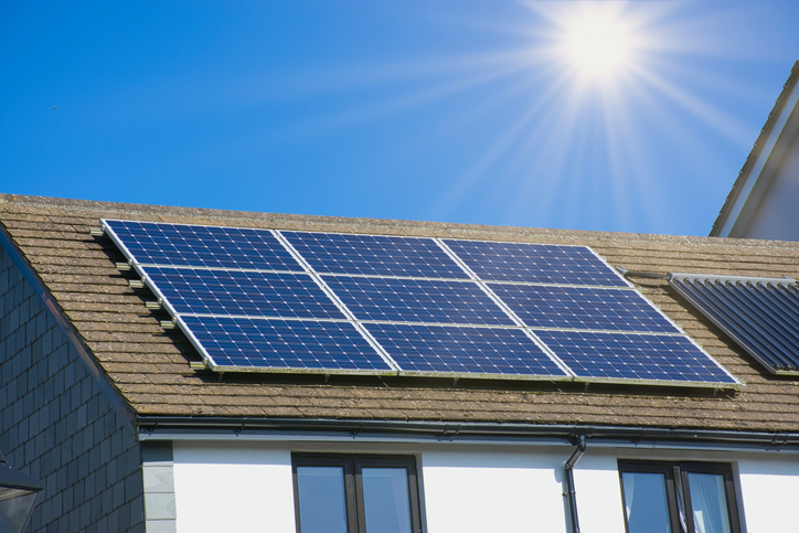 sun rays over a Cornish house with photovoltaic power plant solar panel installers near me