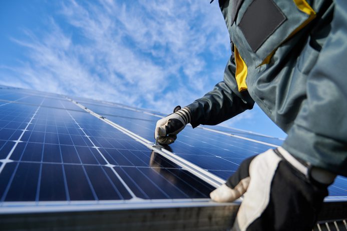 Male worker repairing photovoltaic solar panel.