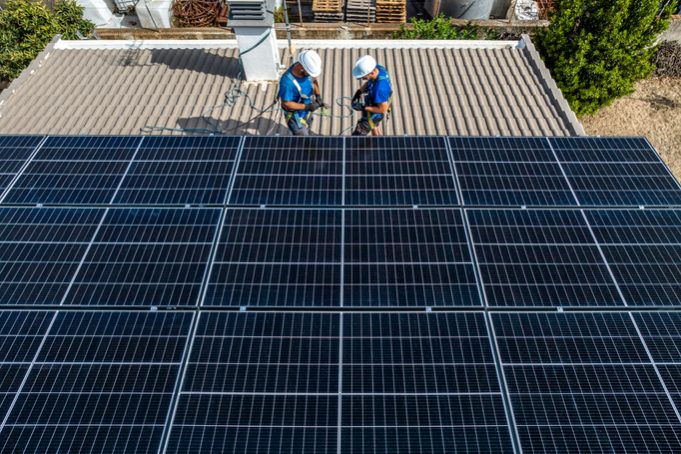 two solar panel installers checking the material in a roof house